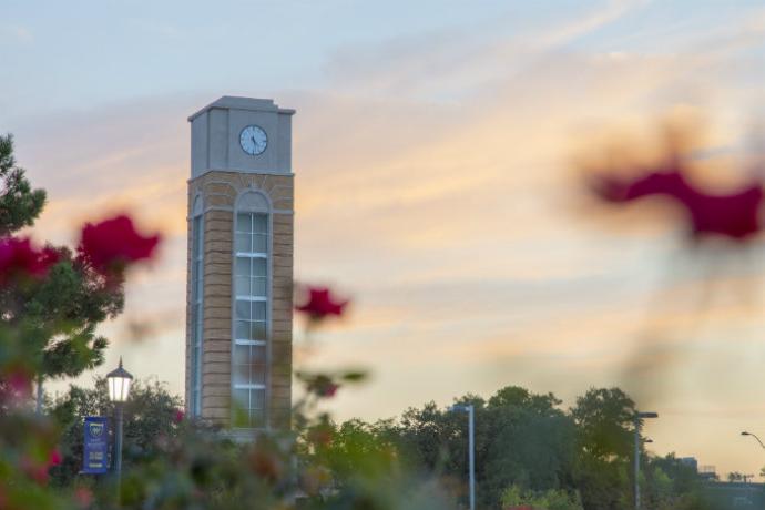 Campus clock tower with red flowers
