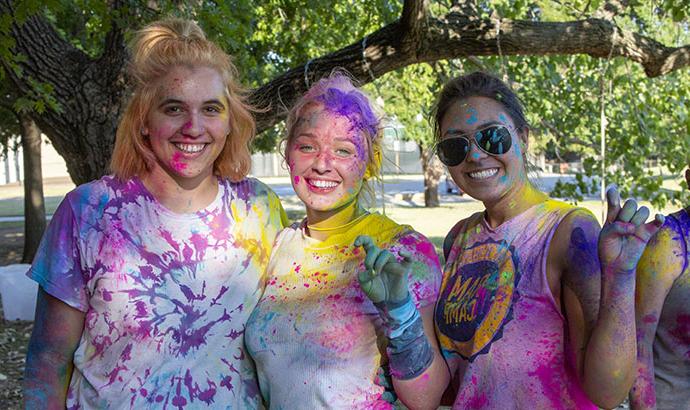 一群学生在一场有趣的活动结束后，身上涂满了彩虹色的粉末