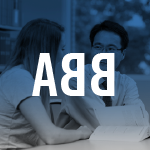 Thumbnail image of a teacher talking to a student while sitting down at a table